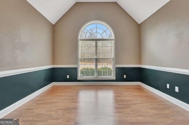 spare room with baseboards, lofted ceiling, and wood finished floors