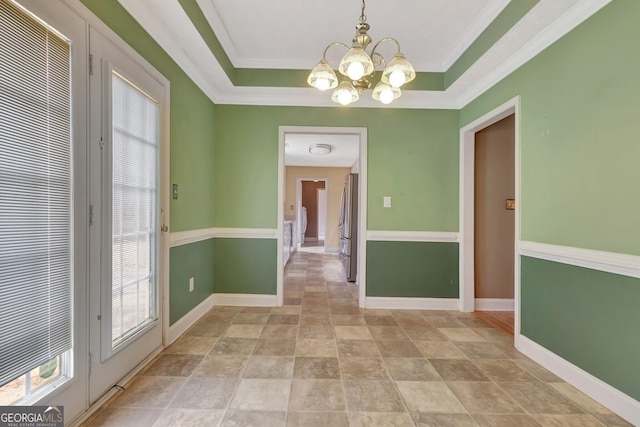 unfurnished dining area featuring a raised ceiling, a notable chandelier, baseboards, and ornamental molding