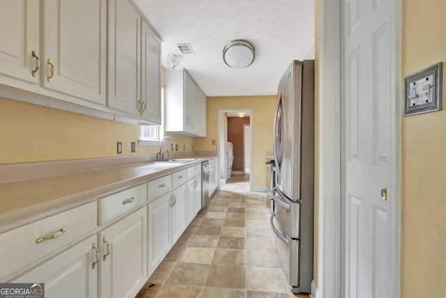 kitchen with visible vents, light countertops, washer / dryer, appliances with stainless steel finishes, and a sink