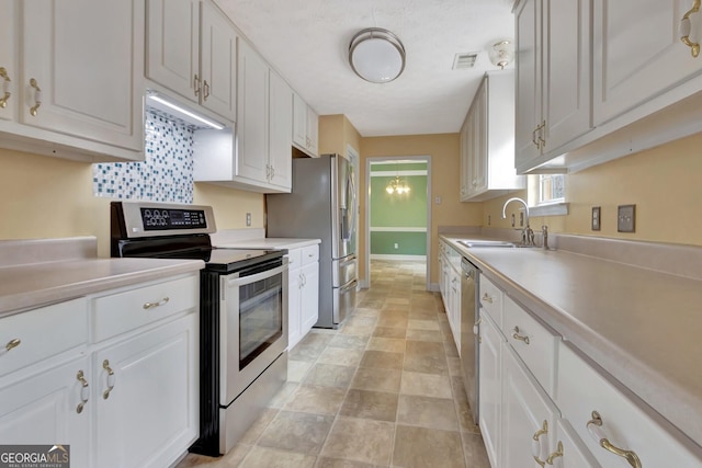 kitchen featuring visible vents, light countertops, white cabinets, stainless steel appliances, and a sink