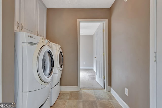 laundry room with cabinet space, light tile patterned floors, washing machine and dryer, and baseboards