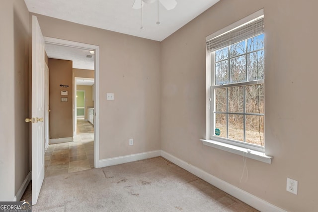 carpeted empty room with baseboards, plenty of natural light, and a ceiling fan