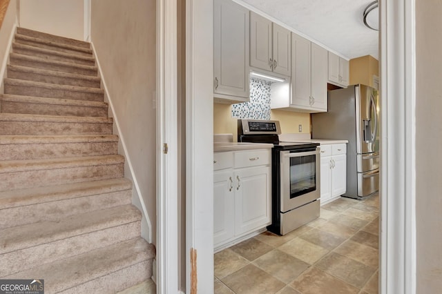 kitchen with baseboards, decorative backsplash, light countertops, white cabinets, and appliances with stainless steel finishes