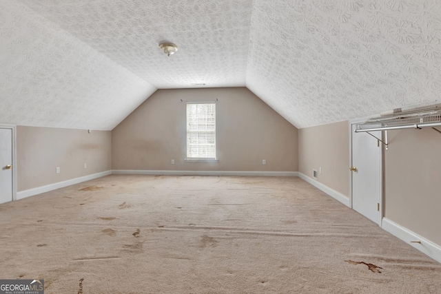 additional living space featuring vaulted ceiling, baseboards, carpet floors, and a textured ceiling