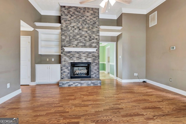 unfurnished living room featuring wood finished floors, baseboards, visible vents, ceiling fan, and crown molding