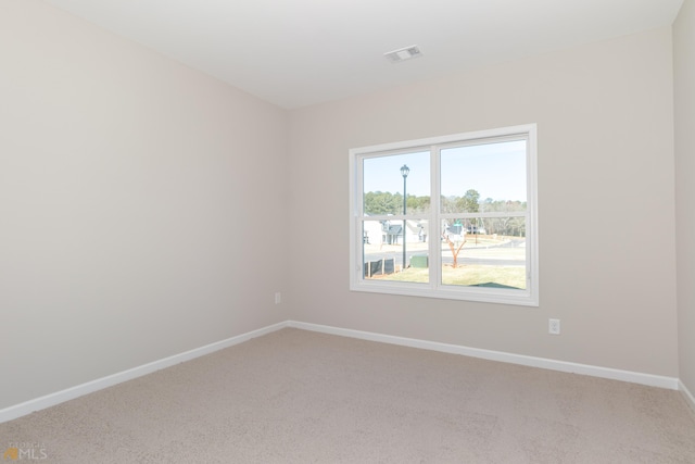 spare room with visible vents, baseboards, and light colored carpet