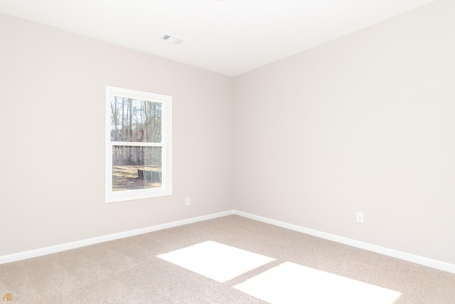 spare room with carpet flooring, visible vents, and baseboards