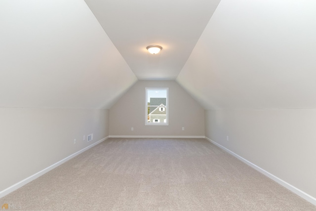 bonus room with lofted ceiling, light colored carpet, baseboards, and visible vents