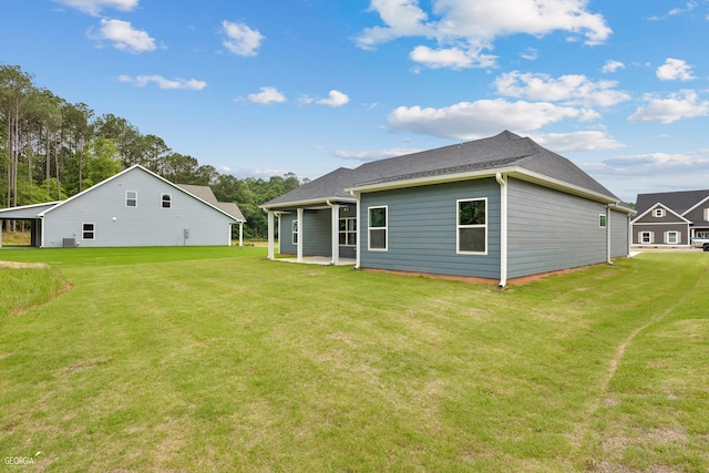 rear view of house with a yard, a patio area, and a shingled roof