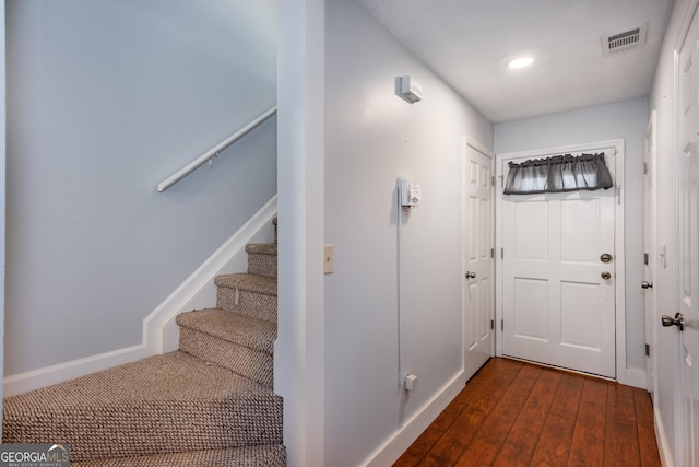 entryway featuring hardwood / wood-style flooring, stairway, baseboards, and visible vents