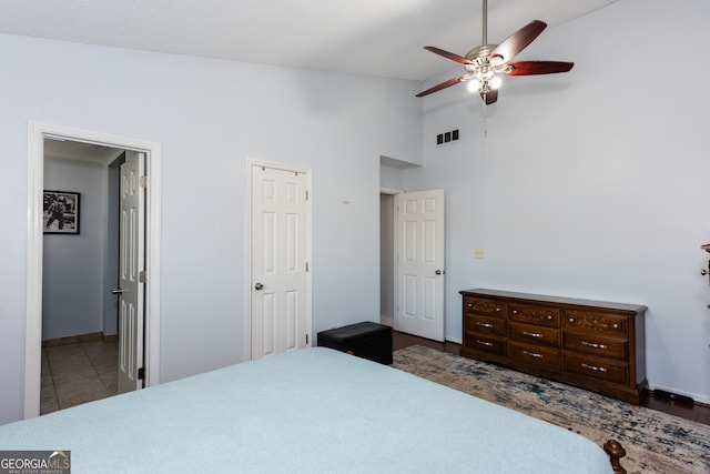 tiled bedroom with visible vents, high vaulted ceiling, ensuite bath, and ceiling fan