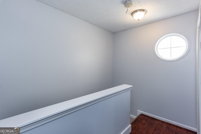 interior space with baseboards, an upstairs landing, a textured ceiling, and dark wood finished floors