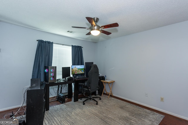 office space featuring visible vents, baseboards, ceiling fan, wood finished floors, and a textured ceiling