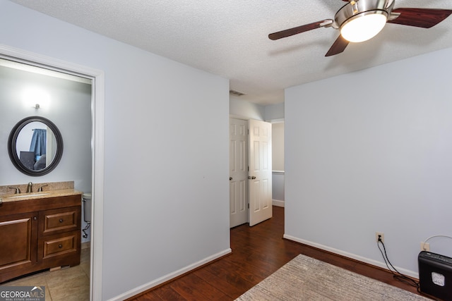 bedroom with visible vents, baseboards, wood finished floors, a textured ceiling, and a sink