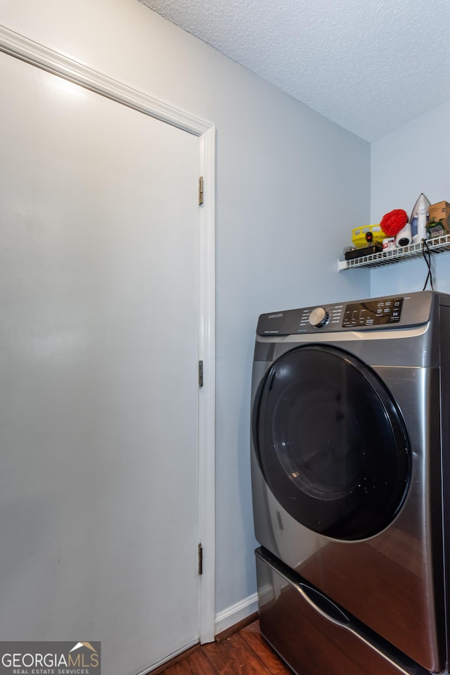 washroom with dark wood-style floors, baseboards, washer / dryer, laundry area, and a textured ceiling