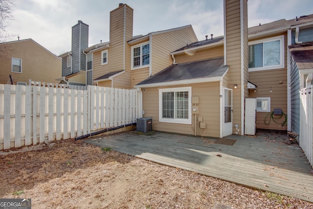 back of house with central air condition unit, fence, a chimney, and a wooden deck