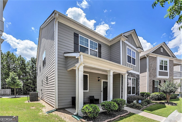 view of front of property featuring a front lawn, covered porch, board and batten siding, and central AC