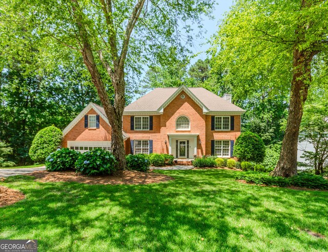 2205 Parliament Dr, Lawrenceville, GA 30043 - colonial home featuring a front lawn, a chimney, and brick siding