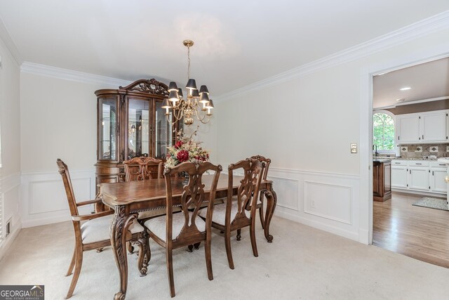2205 Parliament Dr, Lawrenceville, GA 30043 - dining area featuring a chandelier, ornamental molding, light carpet, a decorative wall, and wainscoting