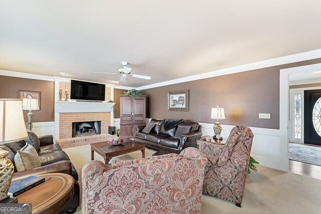 2205 Parliament Dr, Lawrenceville, GA 30043 - living area featuring crown molding, a ceiling fan, light carpet, wainscoting, and a brick fireplace