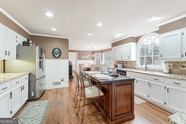 2205 Parliament Dr, Lawrenceville, GA 30043 - kitchen featuring a sink, ornamental molding, stainless steel refrigerator with ice dispenser, white cabinets, and a wainscoted wall