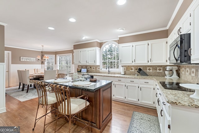 2205 Parliament Dr, Lawrenceville, GA 30043 - kitchen with white cabinetry, black appliances, light stone counters, crown molding, and backsplash