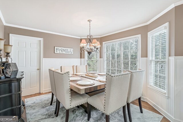 2205 Parliament Dr, Lawrenceville, GA 30043 - dining space with light wood-type flooring, a chandelier, a wainscoted wall, crown molding, and plenty of natural light