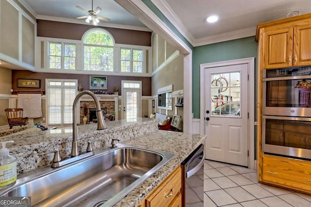 kitchen with ceiling fan, ornamental molding, appliances with stainless steel finishes, light tile patterned flooring, and a sink