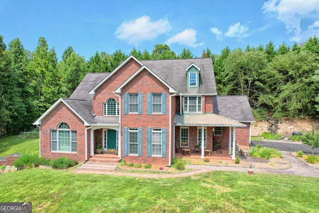 view of front of house featuring brick siding, covered porch, and a front lawn