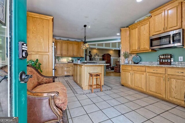 kitchen featuring light tile patterned floors, light brown cabinets, a kitchen island, and stainless steel appliances