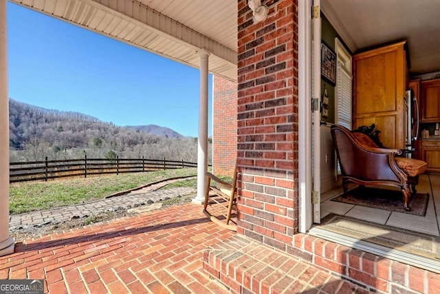 view of patio / terrace with fence and a mountain view