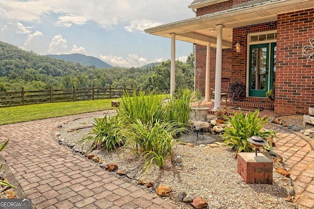 view of patio with a mountain view, a view of trees, and fence