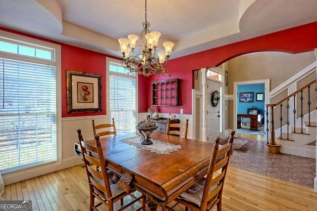 dining space with a raised ceiling, stairway, arched walkways, and wood-type flooring