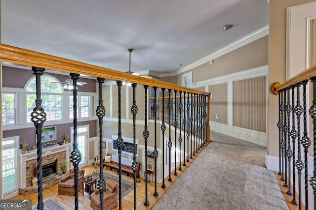 staircase featuring a stone fireplace, baseboards, and ornamental molding