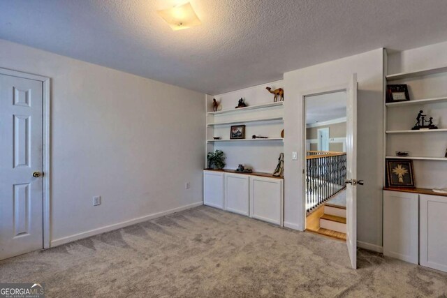 interior space with baseboards, light colored carpet, and a textured ceiling