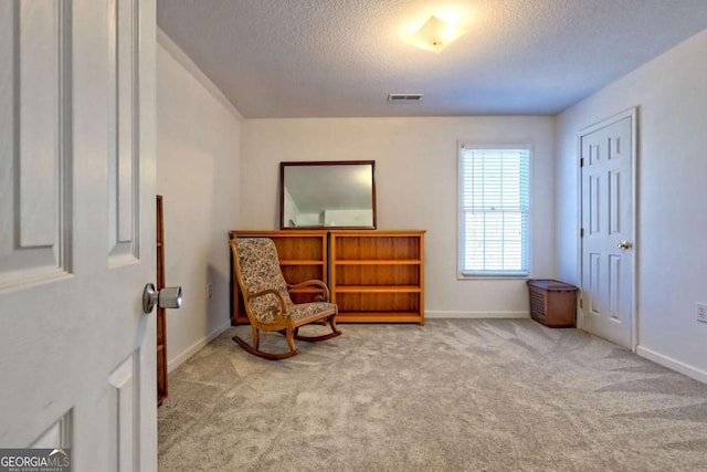 living area featuring baseboards, visible vents, carpet floors, and a textured ceiling