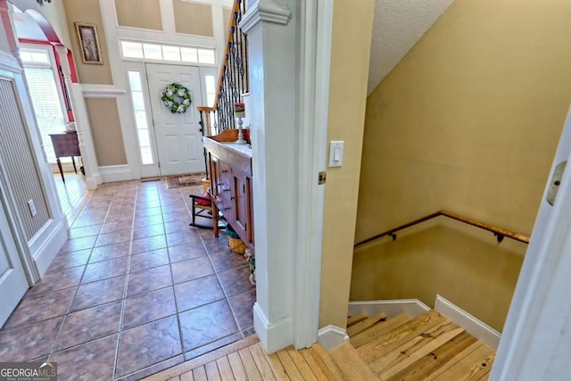 entrance foyer featuring tile patterned floors, stairway, and arched walkways