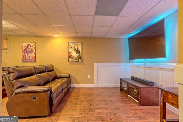 living area with a drop ceiling, baseboards, and wood finished floors