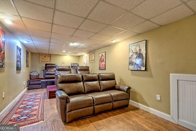 home theater room featuring wood finished floors, baseboards, and a drop ceiling