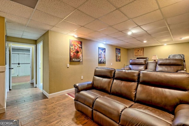 home theater featuring wood finished floors, baseboards, and a paneled ceiling