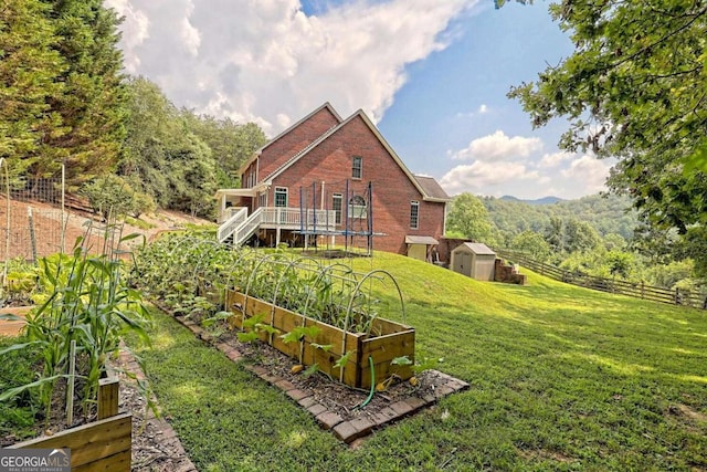 back of house with a lawn, fence, a shed, a vegetable garden, and an outdoor structure