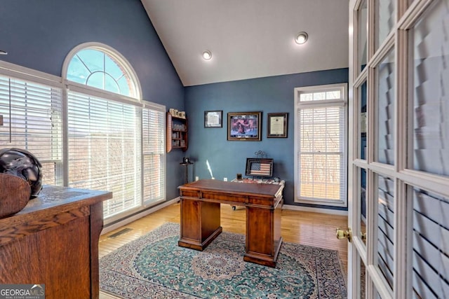 office featuring visible vents, baseboards, high vaulted ceiling, and wood finished floors