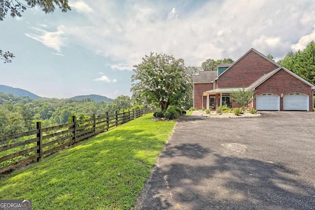 view of front of property featuring a front yard, fence, an attached garage, aphalt driveway, and brick siding