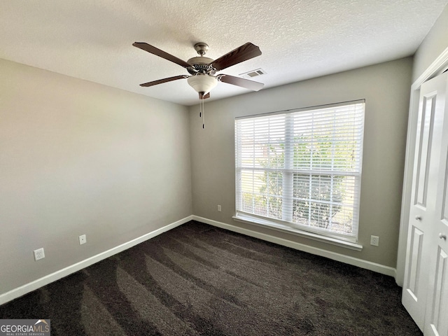 spare room with visible vents, dark carpet, a ceiling fan, and baseboards