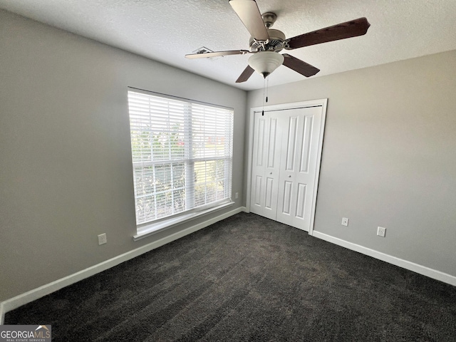 213 Augusta Way, Hinesville, GA 31313 - unfurnished bedroom featuring baseboards, dark colored carpet, a textured ceiling, a closet, and a ceiling fan