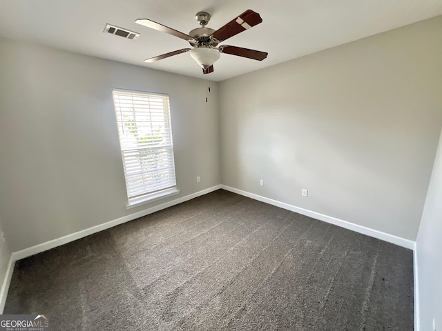 empty room featuring visible vents, dark carpet, a ceiling fan, and baseboards