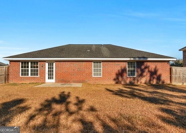 back of property with a yard, brick siding, and fence