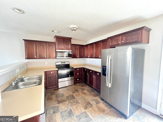 kitchen with visible vents, light countertops, appliances with stainless steel finishes, a textured ceiling, and a sink