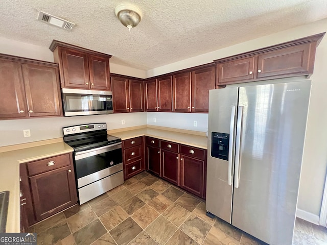 kitchen featuring stainless steel appliances, a textured ceiling, visible vents, and light countertops