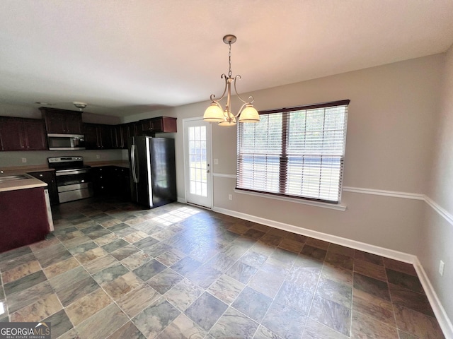 kitchen with baseboards, a sink, stainless steel appliances, light countertops, and a chandelier